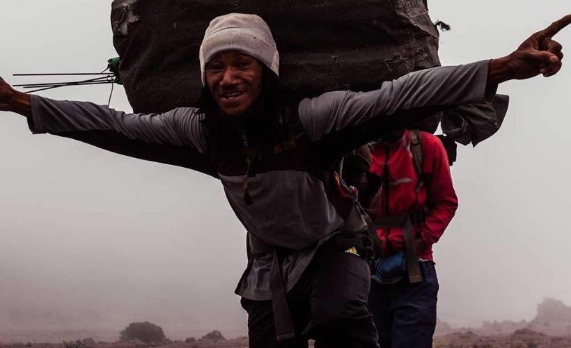 Glad bärare på väg mot Kilimanjaro